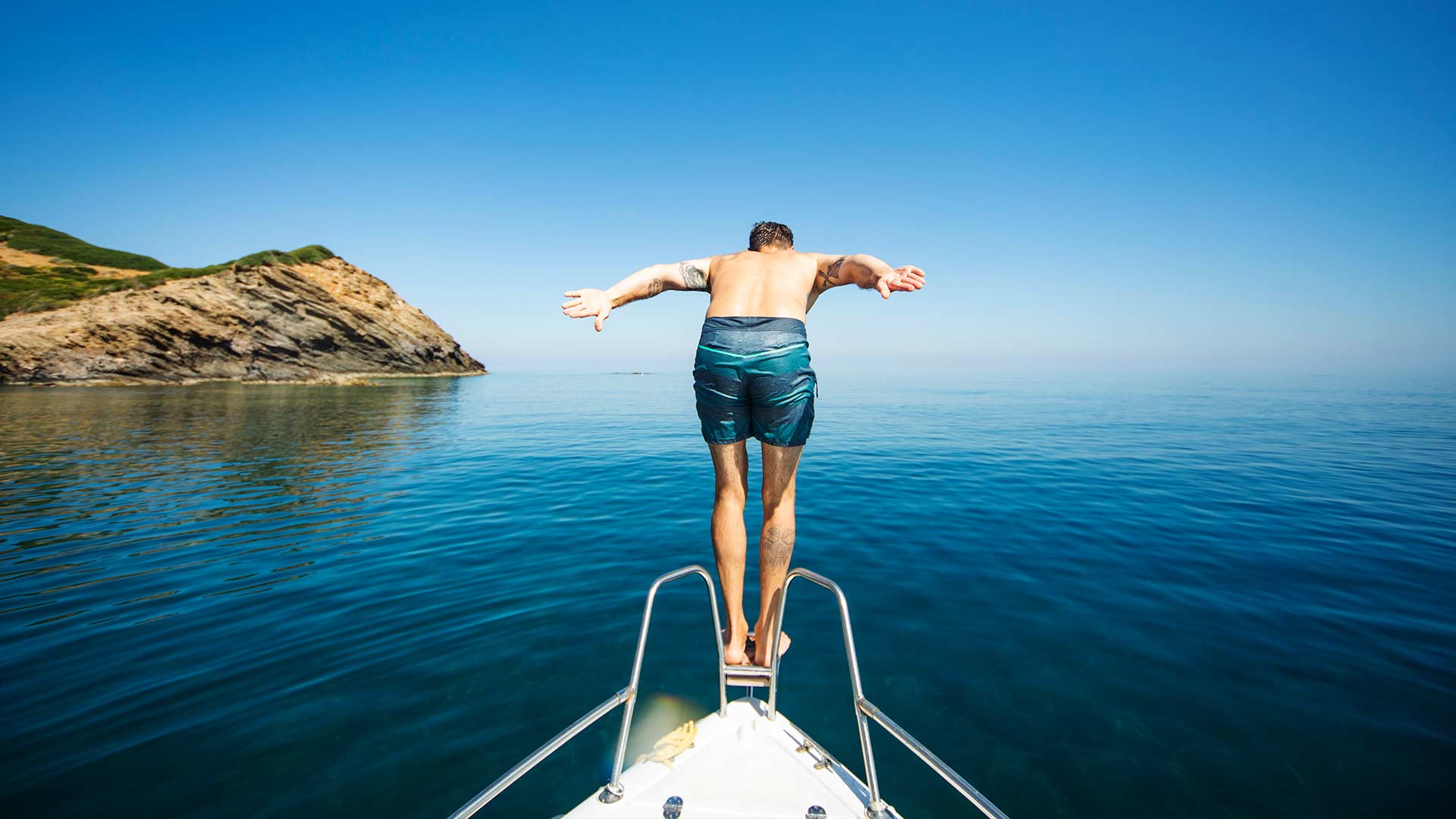 Man diving off the front of a boat into water